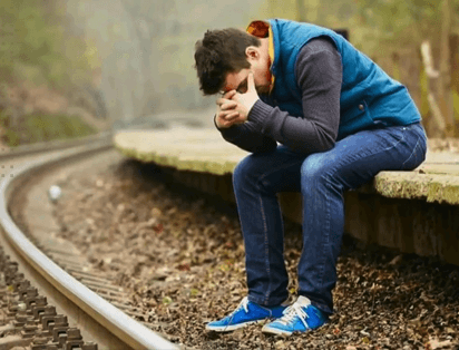 upset man sitting by train tracks